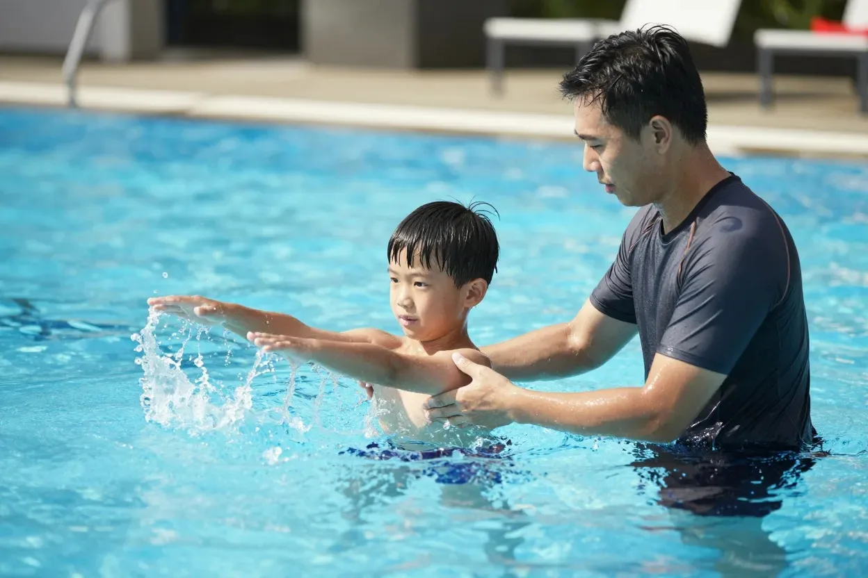 Coach correcting a boy's stroke technique during a swimming lesson