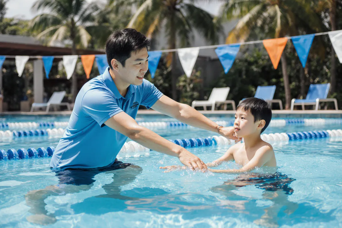 Coach checking a young swimmer arm technique at an ActiveSG pool